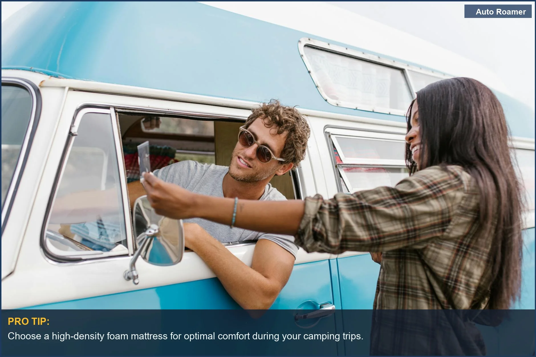 Happy couple on a road trip in a vintage blue VW Transporter camper van, embracing the van life lifestyle.