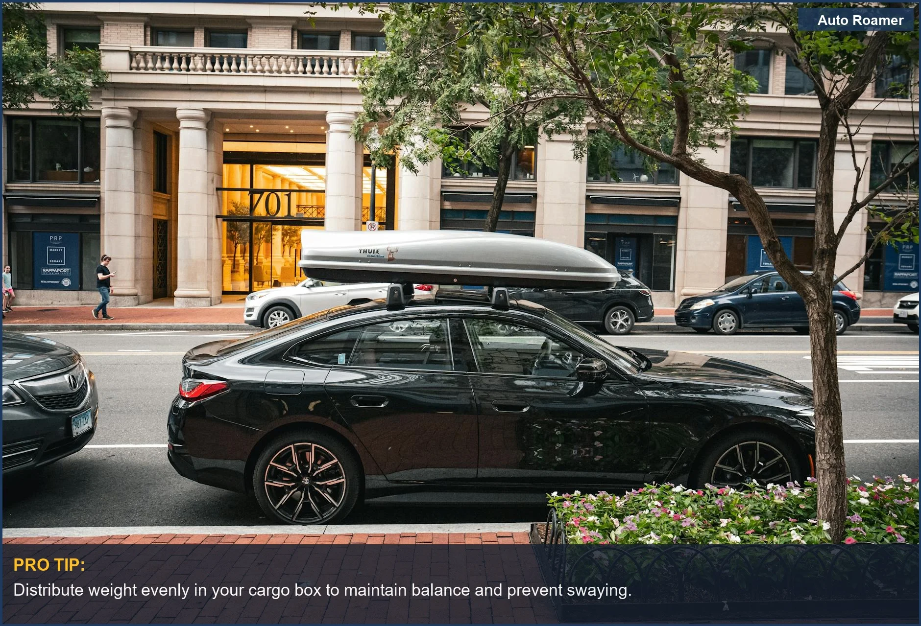 Black sedan parked in city with a rooftop cargo box, illustrating urban cargo solutions.