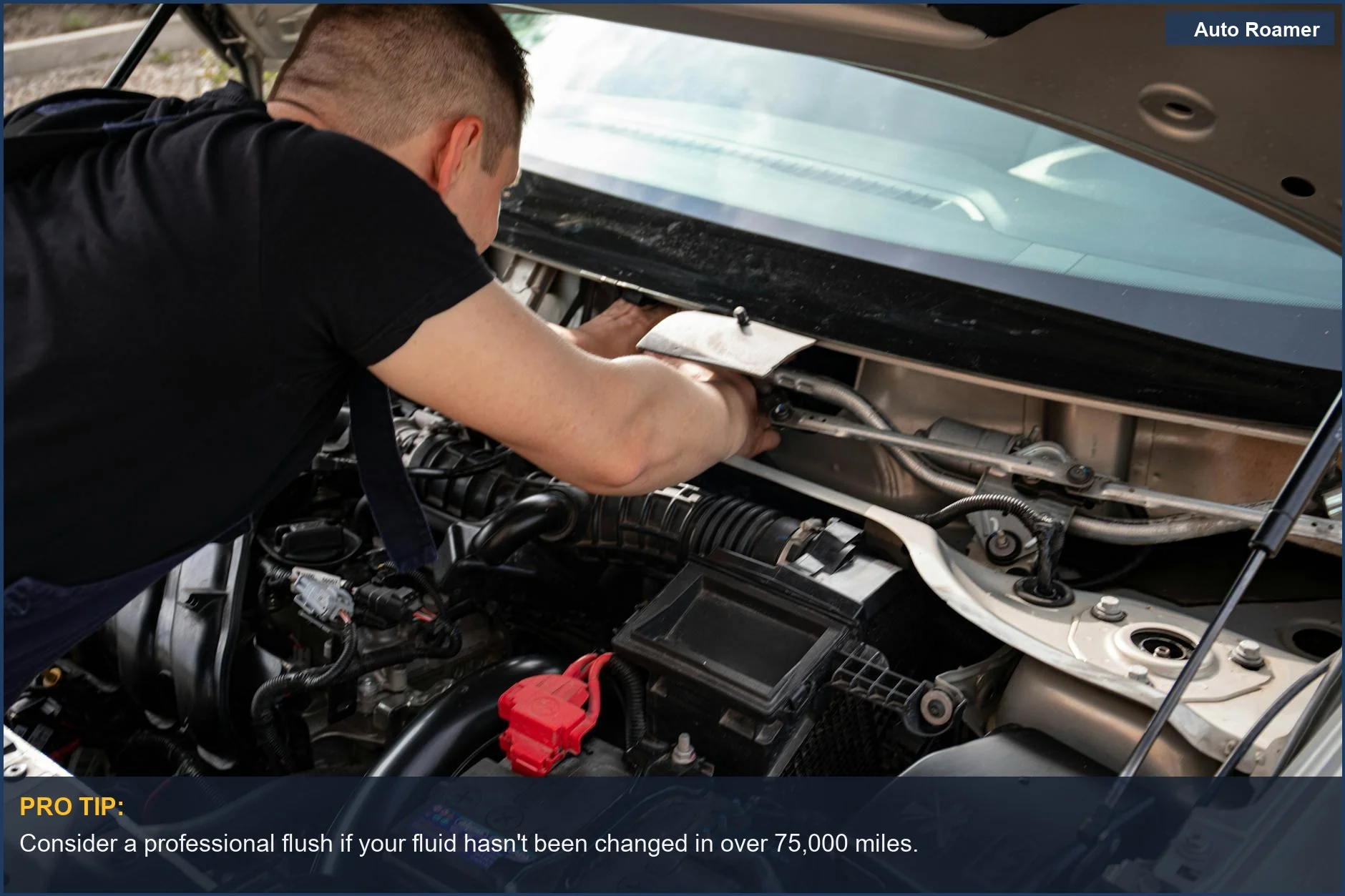 Mechanic actively repairing a car engine under the hood in a busy garage setting.