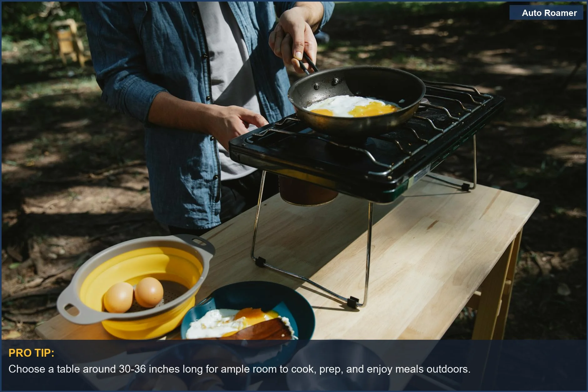 Overhead view of a male camper frying eggs on a stove on a table, emphasizing sufficient workspace.