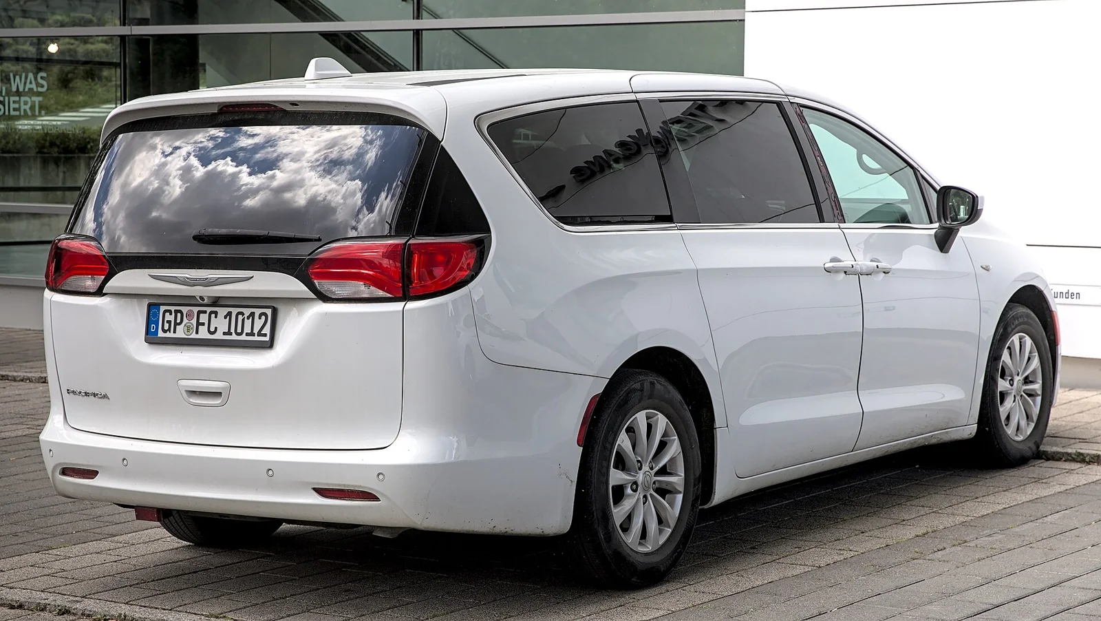 White Chrysler Pacifica, current generation, rear three-quarter view showing the tailgate and tail lights.