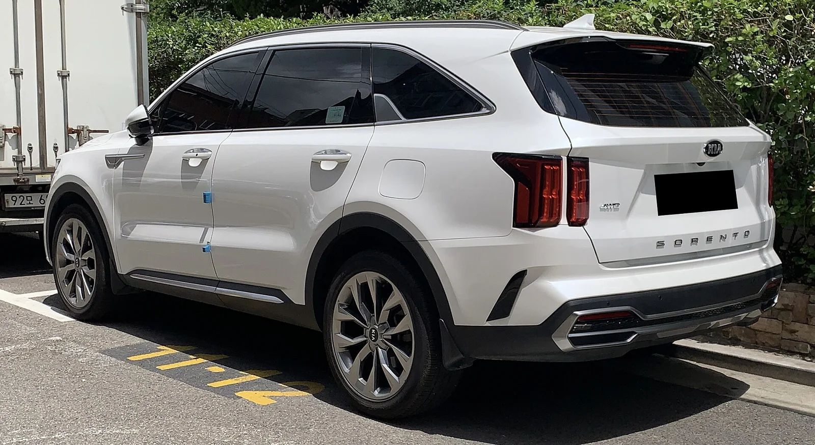 White Kia Sorento, current fourth-generation MQ4, rear three-quarter view showing the tailgate and vertical tail lights.