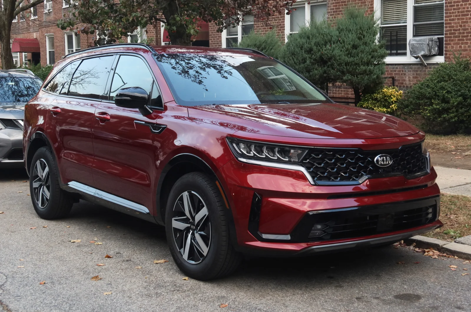 Dark-red Kia Sorento, current fourth-generation MQ4, front three-quarter view showing the tiger-nose grille.