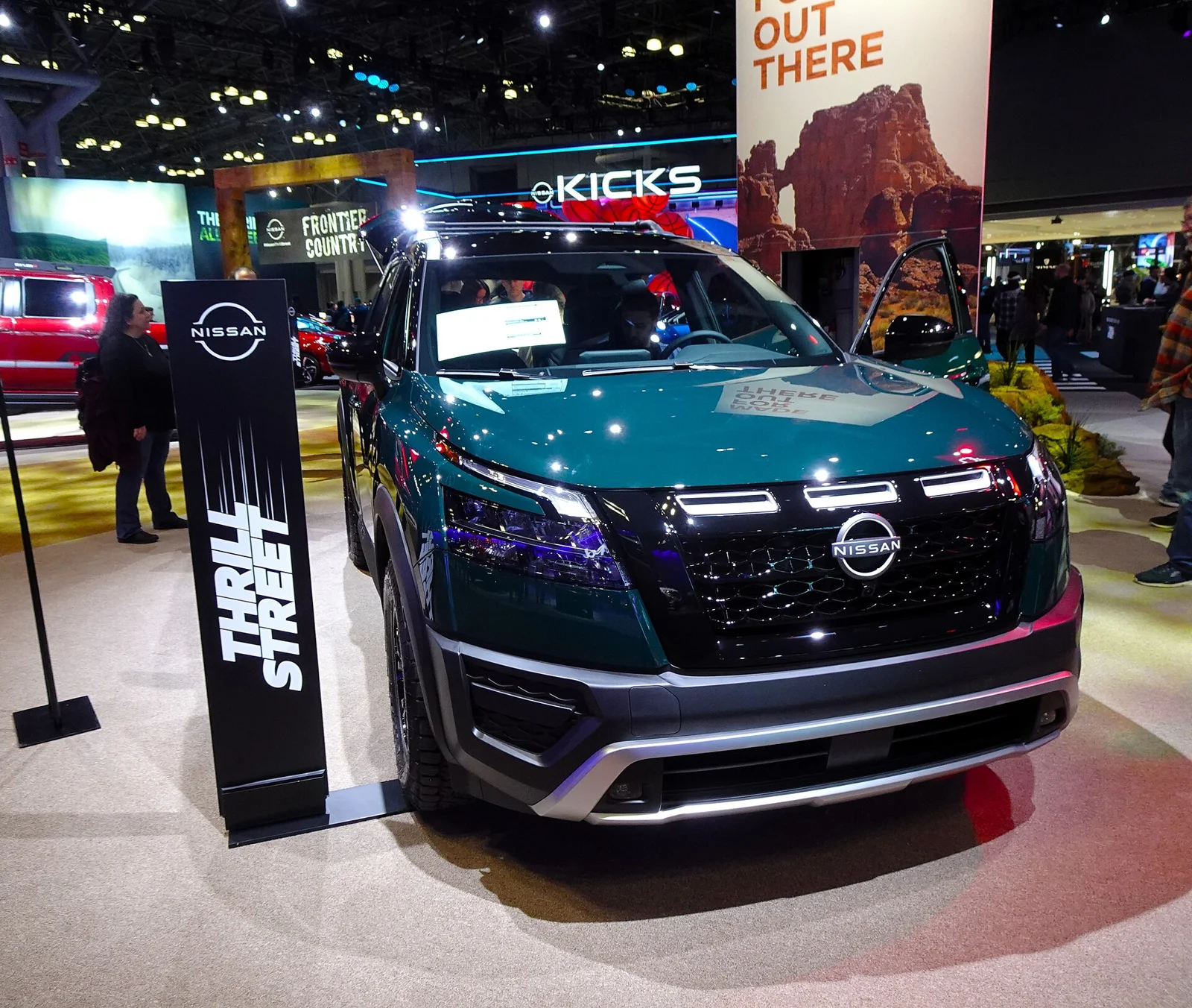 Teal Nissan Pathfinder, current R53 generation, front three-quarter view on a show stand.