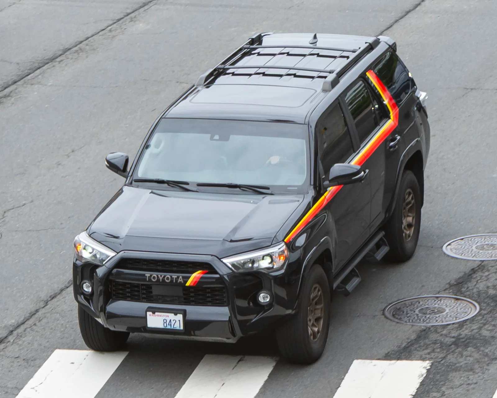 Grey Toyota 4Runner TRD, current sixth generation, front three-quarter view with an orange accent stripe crossing a crosswalk.