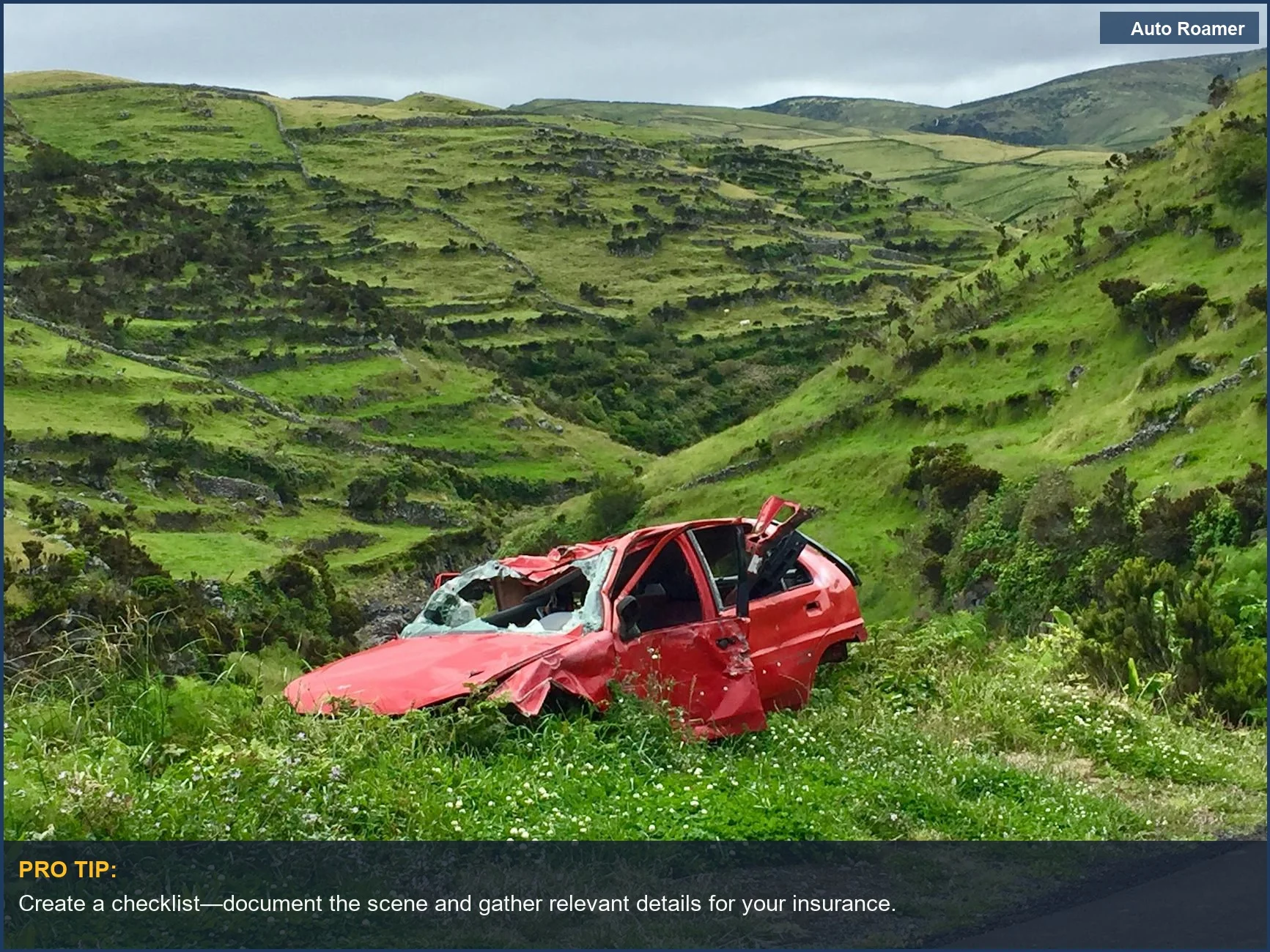 Abandoned red wrecked car in a scenic green valley, depicting the aftermath of a car accident.