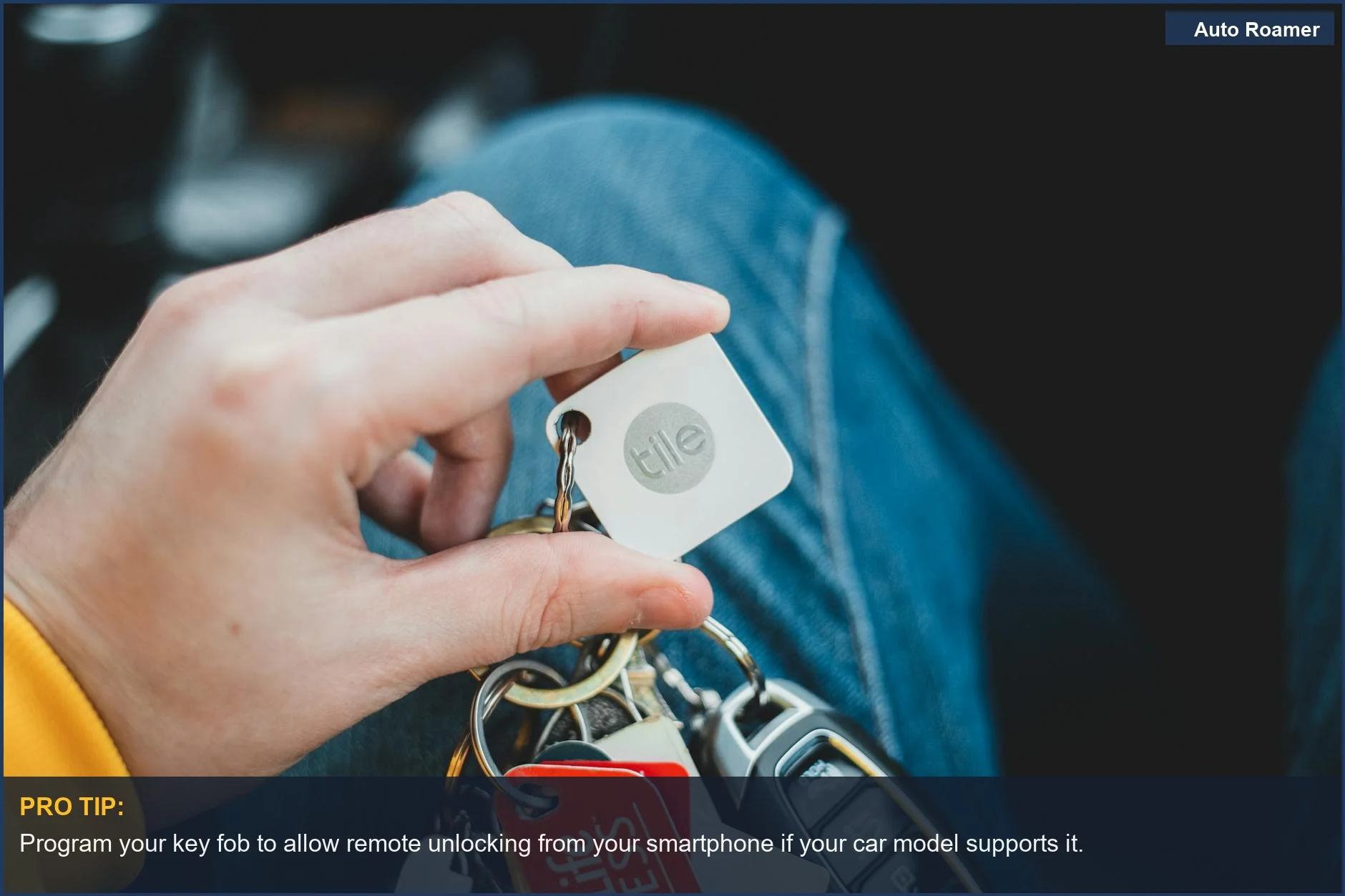 Hand holding a set of car keys with multiple keychains and tags indoors, ready for a drive.