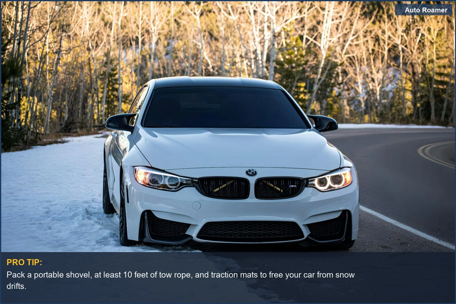 Modern white car on a snowy road with trees, illustrating the need for a winter car emergency kit for mountain passes.