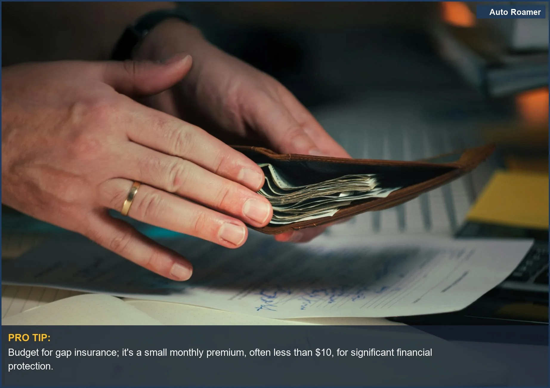 Hands hold a wallet full of cash over documents, symbolizing smart financial planning and the importance of gap insurance necessity.