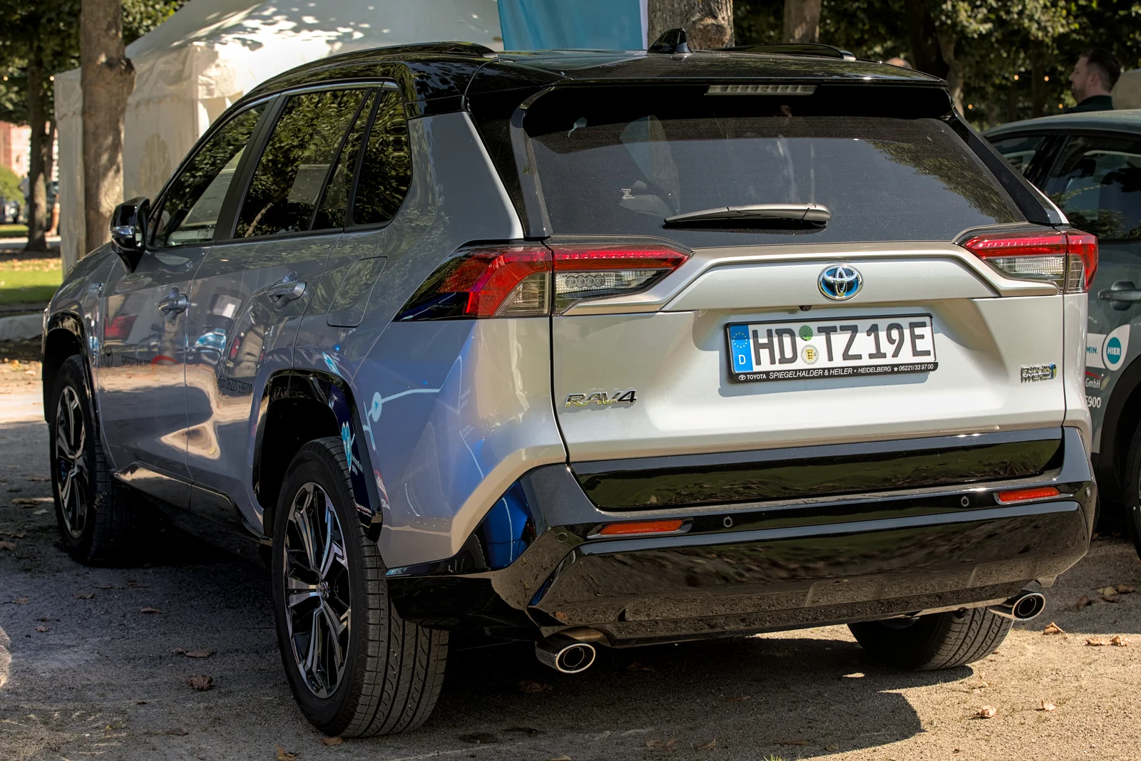 Silver Toyota RAV4 Hybrid, current fifth-generation XA50, rear three-quarter view with roof rails.