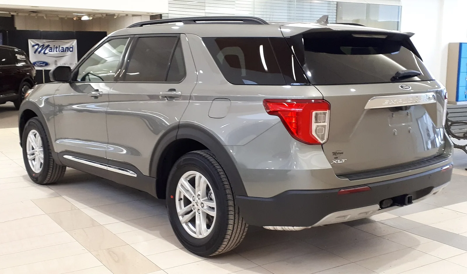A grey Ford Explorer, current sixth generation, rear three-quarter view showing the tail-lights.