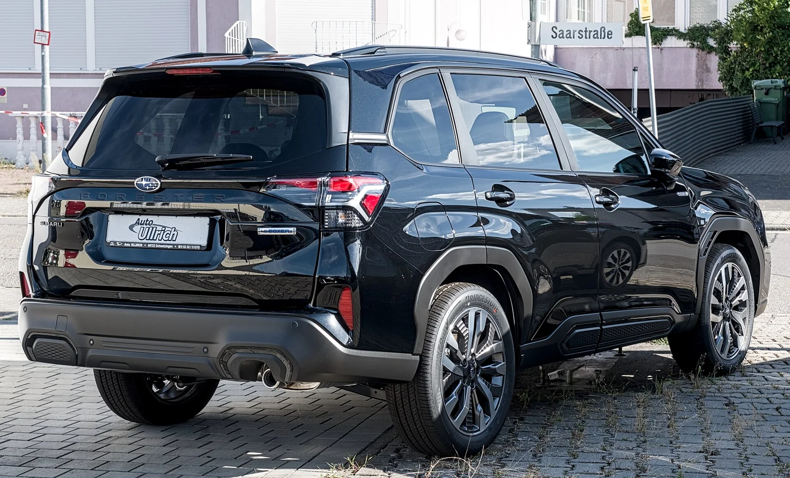 Dark-blue Subaru Forester, current sixth generation, rear three-quarter view on a city street.