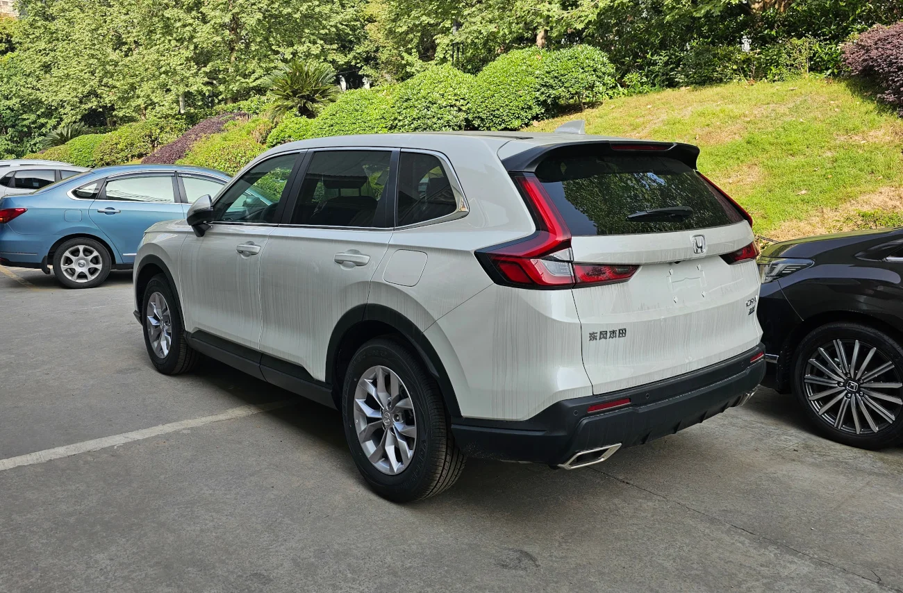 White Honda CR-V, current sixth generation, rear three-quarter view showing the vertical tail lights and tailgate.