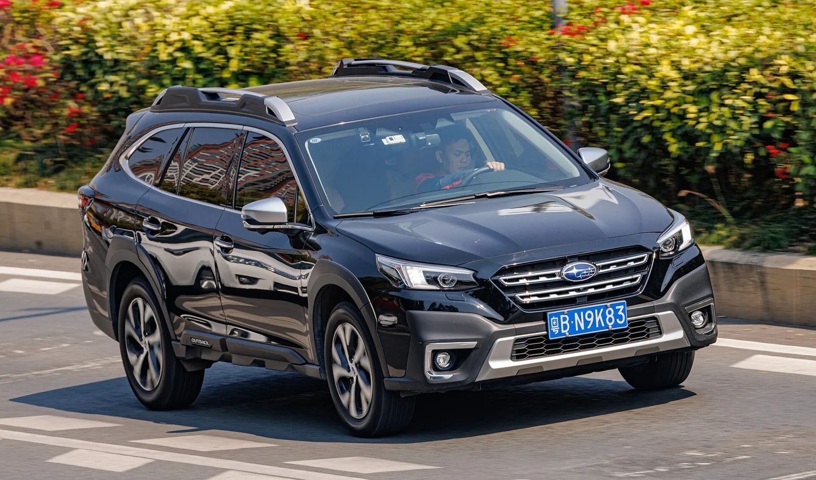 Dark-blue Subaru Outback, current sixth-generation, front three-quarter view with black roof rails.