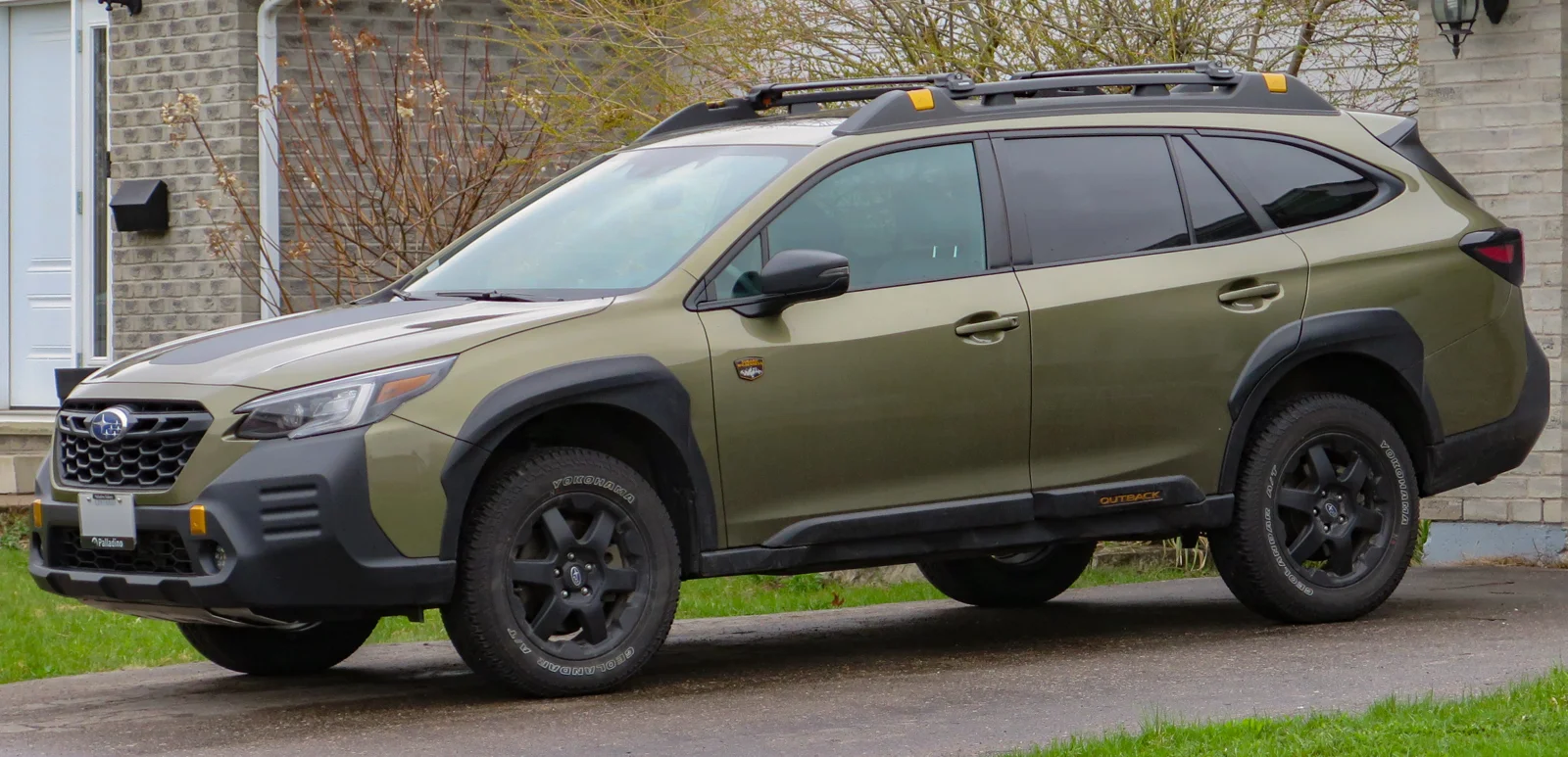 Green Subaru Outback Wilderness, current sixth-generation, front three-quarter view with raised suspension and roof rails.