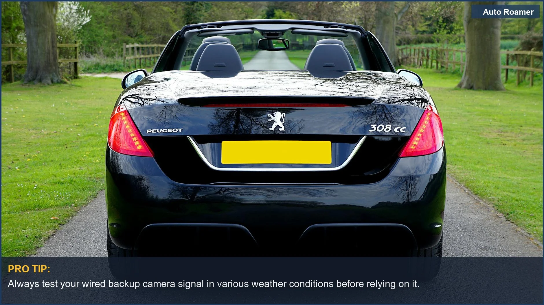 Rear view of a black Peugeot convertible on a scenic countryside road, ideal for demonstrating backup camera visibility.