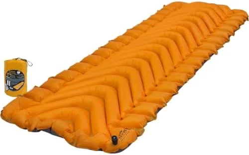 An orange Klymit Insulated Static V Lite inflatable pad beside its packed stuff sack on a plain background.